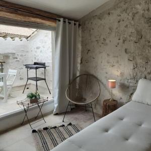 a bedroom with a bed and a chair and a table at Maison Centre Historique Bize Minervois + Terrasse in Bize-Minervois