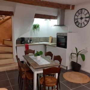 a kitchen with a table and chairs and a clock at Maison Centre Historique Bize Minervois + Terrasse in Bize-Minervois