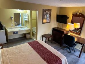 um quarto de hotel com uma cama, uma secretária e uma casa de banho em Wye Motel em Clinton