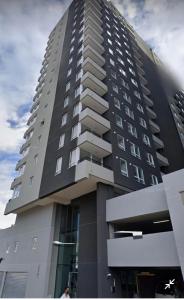 a tall building with people standing in front of it at Apart Center Temuco in Temuco