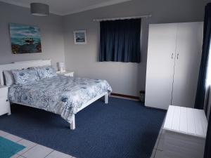 1 dormitorio con 1 cama y alfombra azul en À La Mer - Selfcatering Unit, en Agulhas