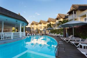 una piscina in un resort con sedie e ombrelloni di Hôtel Exsel Ermitage a Saint-Gilles-les Bains