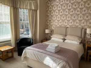 a bedroom with a bed and a chair and windows at Glenora Guest House in Whitby