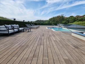 una terraza de madera con sillas y una piscina en Zimbali Lakes Boulevard Suites, en Ballito