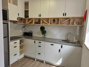 a kitchen with white cabinets and a sink at Curtido House Suits in Ílhavo