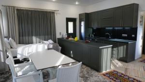 a kitchen with black cabinets and a white table at Giorgos’s Luxury Apartment. in Leonidio