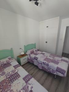 two beds in a bedroom with purple and white sheets at L'Olivar in Port de la Selva