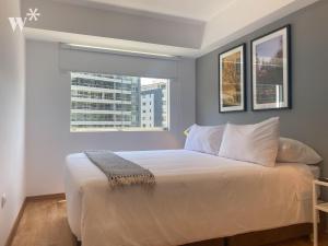 a bedroom with a large bed with two windows at Classy 2BR in Miraflores in Lima
