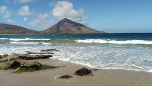 a beach with rocks and a mountain in the ocean at Foreen Lodge, Achill Island in Achill