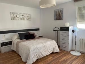 Biała sypialnia z łóżkiem i wentylatorem w obiekcie Apartamento familiar Alhambra Granada w Grenadzie
