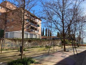 huśtawka w parku z drzewami i budynek w obiekcie Apartamento familiar Alhambra Granada w Grenadzie