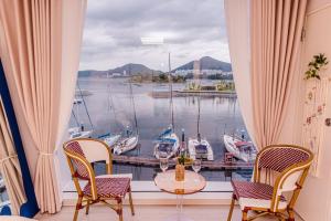 a window with a table and chairs and boats in the water at The castle ocean suite in Yeosu