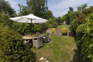 a table and chairs with an umbrella in a garden at Rose Cottage in Burnham Thorpe