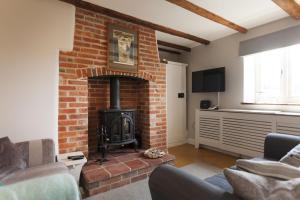 uma sala de estar com uma lareira de tijolos e um fogão em Rose Cottage em Burnham Thorpe