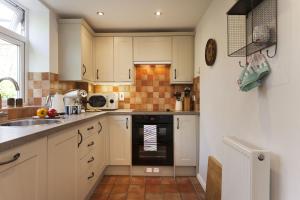 a kitchen with white cabinets and a black oven at Rose Cottage in Burnham Thorpe