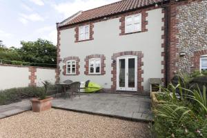 a white house with a patio with a table and chairs at Legion Cottages in Blakeney