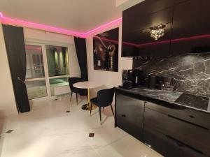 a kitchen with black cabinets and a table with chairs at Premium Sky Jacuzzi Apartment in Klaipėda