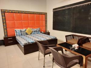a bedroom with a bed and a table and chairs at Capital Lodge Gulistan-e-Johar in Karachi