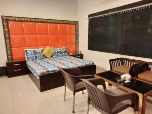 1 dormitorio con 1 cama, mesa y sillas en Capital Lodge Gulistan-e-Johar, en Karachi