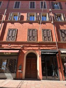 ボローニャにあるPiazza Maggiore Luxury Apartmentの茶色の扉と窓のあるオレンジ色の建物