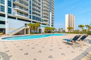 a swimming pool with two chairs and a building at Emerald Dolphin 0640 in Pensacola Beach