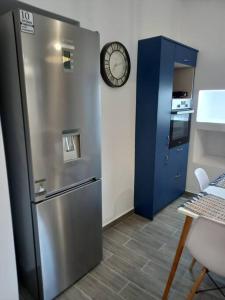 a kitchen with a refrigerator and a clock on the wall at Dipotamata House SynetI in Andros