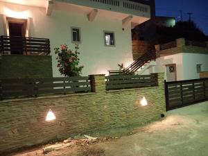 a building with a fence and a wall with lights at Dipotamata House SynetI in Andros