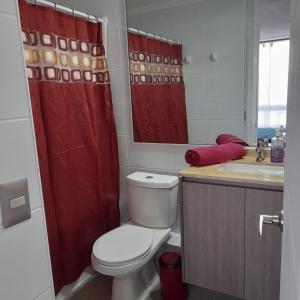 a bathroom with a toilet and a red shower curtain at Departamento diario pleno centro vista al mar in Iquique