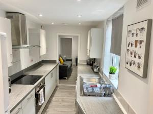 a white kitchen with a sink and a couch at Emerald Properties UK - Stoke-on-Trent City Centre, close to Alton Towers in Stoke on Trent