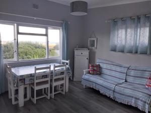 a bedroom with a table and a couch and a window at À La Mer - Selfcatering Unit in Agulhas