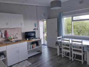 a kitchen with white cabinets and a table and a window at À La Mer - Selfcatering Unit in Agulhas