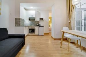 Una sala de estar con un sofá negro y una mesa. en Encantador apartamento con patio, en Málaga