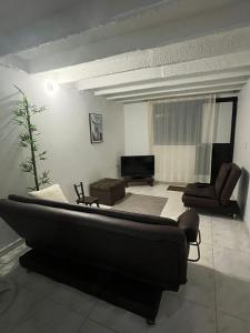 sala de estar con sofá negro y sillas en Casa de Descanso El Diamante, en Restrepo