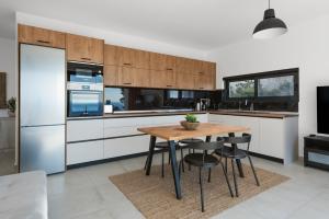 a kitchen with white cabinets and a wooden table at Aquarama Pool Apartments in Ixia