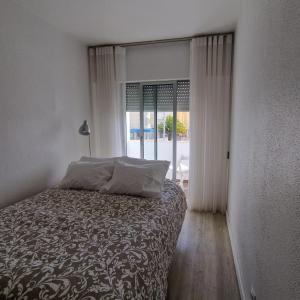 ein Schlafzimmer mit einem Bett und einem großen Fenster in der Unterkunft Casinhas da Praia in São Martinho do Porto