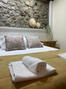 a white towel on a bed with a stone wall at Pensión liebana in San Vicente de la Barquera
