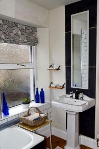 een badkamer met een wastafel, een spiegel en een bad bij Beval Cottage in Abergavenny