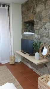 a living room with a tv on a stone wall at Pensión liebana in San Vicente de la Barquera