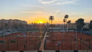 a sunset over a tennis court with palm trees at Rooms on Malvarrosa beach in Valencia
