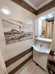 a bathroom with a sink and a picture of a lighthouse at Апартаменти за гости Делукс in Burgas City +107 photos