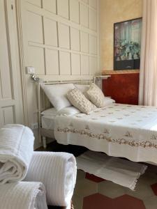 a white bedroom with two beds and a chair at B&B Villa le Ortensie in Faggeto Lario 