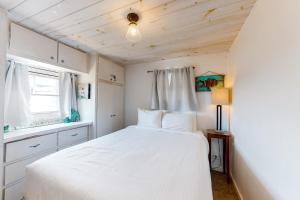 um quarto com uma cama branca e uma janela em 3rd Street Beach Retreat em Mexico Beach
