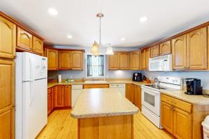 una cocina con armarios de madera y electrodomésticos blancos en Cherry Valley Retreat, en Gilford