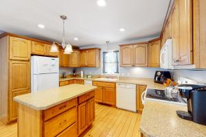 a kitchen with wooden cabinets and a white refrigerator at Cherry Valley Retreat in Gilford +13 photos