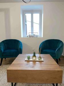 uma sala de estar com duas cadeiras azuis e uma mesa de madeira em L’insolite airbnb em Vignieu