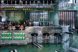 a bar with black stools in a room with green tiles at San Francisco Proper Hotel, a Member of Design Hotels in San Francisco