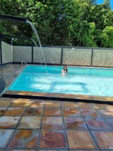 a woman in a swimming pool with a fountain at Flats quase beira mar ar piscinas estac caseiro in Itamaracá