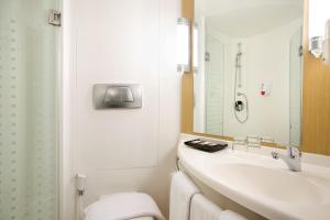 a bathroom with a sink and a toilet and a mirror at Ibis Bandung Pasteur in Bandung