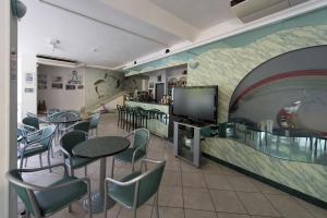 a restaurant with tables and chairs and a wall with a mural at Hotel Pacific in Rimini