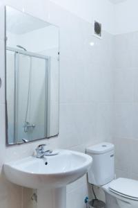 uma casa de banho com um lavatório, um espelho e um WC. em 2 bdr cozy beachside apartment, Copacabana - LCGR em Mindelo